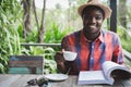 African man reading a book with holding a hot coffee.World book day Concept