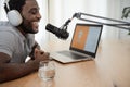 African man recording a podcast using microphone and laptop from home studio Royalty Free Stock Photo