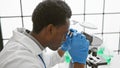 African man scientist analyzing samples under a microscope in a modern laboratory Royalty Free Stock Photo