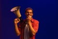 African man screaming in megaphone, making announcement isolated over neon blue background Royalty Free Stock Photo