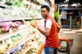 African man shopping in vegetable section at supermarket. Black man doing shopping at market while buying vegetables Royalty Free Stock Photo