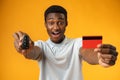 African man showing car key and credit card over yellow background Royalty Free Stock Photo