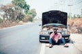 African man sits with his hand over his head as his car breaks down on the road Royalty Free Stock Photo