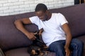 African man sitting on couch playing with dachshund at home Royalty Free Stock Photo