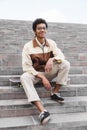 African man skateboarder sitting on his skateboard