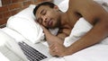 African Man Sleeping Near Laptop in Bed for Rest Royalty Free Stock Photo