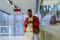 African man with smartphone in airport terminal, young black guy traveler waiting for plane boarding Royalty Free Stock Photo