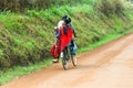 African man transports his wife and child on bicycle, Uganda, Africa