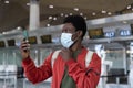 African man using face id feature on smartphone in medical mask in airport at covid-19 quarantine Royalty Free Stock Photo