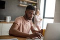 African man using laptop while caucasian girlfriend standing lonely at kitchen Royalty Free Stock Photo