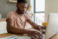 African man using laptop while caucasian girlfriend standing lonely at kitchen Royalty Free Stock Photo