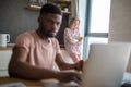 African man using laptop while caucasian girlfriend standing lonely at kitchen Royalty Free Stock Photo