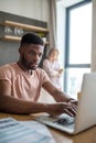 African man using laptop while caucasian girlfriend standing lonely at kitchen Royalty Free Stock Photo