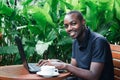 African man using a laptop computer outside a coffee cafe Royalty Free Stock Photo