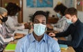 African man wearing face mask in co-working creative space with team work - Young people working during corona virus