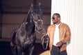 African Man wearing sunglasses near black horse in hangar Royalty Free Stock Photo