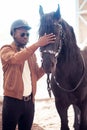 African Man wearing sunglasses near black horse in hangar Royalty Free Stock Photo