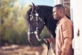 African Man wearing sunglasses near black horse in hangar Royalty Free Stock Photo