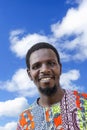 African man wearing a traditional boubou (clothing) and smiling, blue sky, white clouds, photo