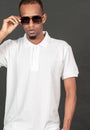 An african man wearing white blank polo shirt, doing a simple pose with one of his hand on his hat Royalty Free Stock Photo