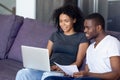 African couple sitting on couch checking bills using computer Royalty Free Stock Photo