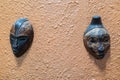 African masks on a orange stucco wall hanging for decoration Royalty Free Stock Photo