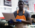 African mechanic man using a laptop computer checking car in workshop Royalty Free Stock Photo