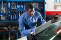 African mechanic man using a laptop computer checking car in workshop Royalty Free Stock Photo