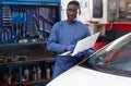 African mechanic man using a laptop computer checking car in workshop Royalty Free Stock Photo