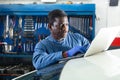 African mechanic man using a laptop computer checking car in workshop Royalty Free Stock Photo