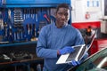 African mechanic man using a laptop computer checking car in workshop Royalty Free Stock Photo