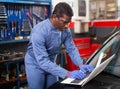 African mechanic man using a laptop computer checking car in workshop Royalty Free Stock Photo