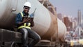 African mechanical engineer looks at tablet to maintain train in city center with tall buildings in the background