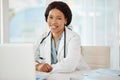 African medical doctor working at a hospital, planning on a laptop and sitting at a desk in an office. Portrait of a Royalty Free Stock Photo