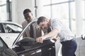 An African man who buys a new car checks a car talking to a professional vendor.