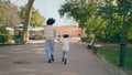 African mother daughter running down park road sunny day. Back view happy family Royalty Free Stock Photo