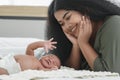 African mother and new born baby in diaper on a white bed. Young mom smile and looking at her little infant boy sleepi Royalty Free Stock Photo