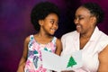 African mother reading christmas card to little girl.