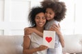 African mum hugging daughter holding greeting card on mothers day Royalty Free Stock Photo