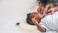 African newborn baby is 2 months old lying on a white bed smiling happily When he is looking at his mother Royalty Free Stock Photo