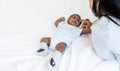 African newborn baby is 2 months old lying on a white bed smiling happily When he is looking at his mother Royalty Free Stock Photo