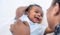 African newborn baby is 2 months old lying on a white bed smiling happily When he is looking at his mother Royalty Free Stock Photo