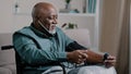 African old man elderly grandfather sitting in wheelchair measuring high low blood pressure mature male patient at home Royalty Free Stock Photo