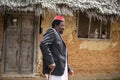 An African Older Man in Red Muslim Taqiyyah Fez Hat And Blazer on white Dress Moving a stick for lame people Near the