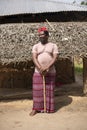 An African Older Man in Red Muslim Taqiyyah Fez Hat posing with a stick for lame people on Yard Near the Basic Hut with