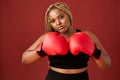 African oversize woman with red boxing mitts isolated on red background