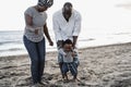 African parents and little son having fun on the beach at sunset - Focus on father Royalty Free Stock Photo