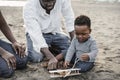 African parents and little son having fun with wood airplane on the beach - Main focus on kid face