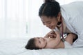 African pediatrician doctor with stethoscope playing with adorable little 3 month newborn baby girl. Smiling cute infant lying in Royalty Free Stock Photo