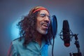 African Rastafarian singer male wearing a blue shirt and beanie emotionally writing song in the recording studio. Royalty Free Stock Photo